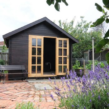 Kitset Cabin painted black with lavender plants