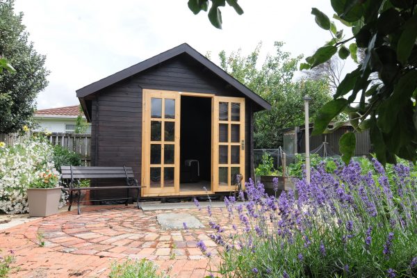 Kitset Cabin painted black with lavender plants
