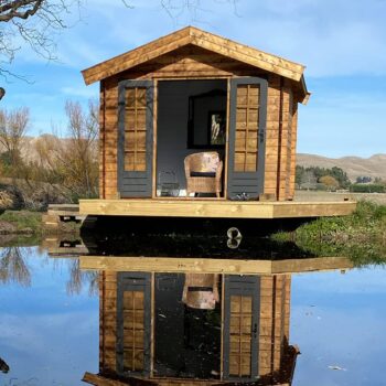 wooden kitset cabin on jetty by lake side